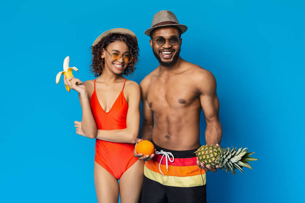 新鮮な夏の果物を楽しむ陽気な黒人の男女 - 写真・画像