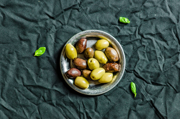 Teller mit reifen Oliven vor schwarzem Hintergrund - Foto, Bild