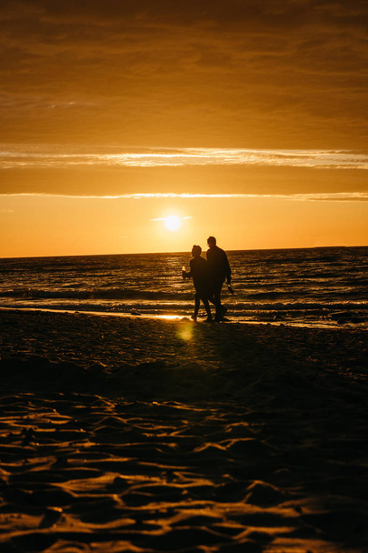 Silueta de personas caminando sobre la puesta de sol sobre el mar Báltico
.  - Foto, imagen