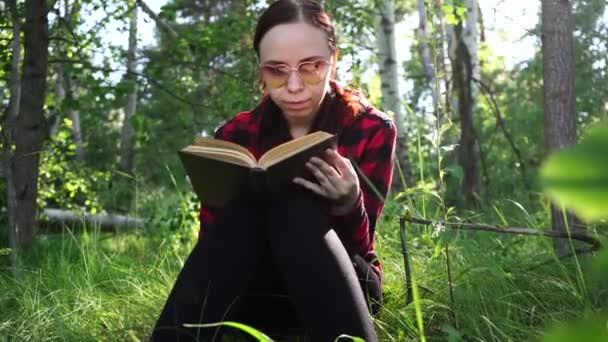 Woman reading a book in a green summer forest. - Felvétel, videó