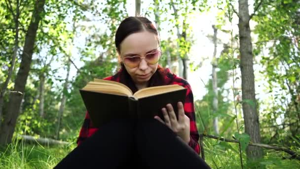 Woman reading a book in a green summer forest. - Záběry, video