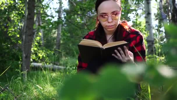Woman reading a book in a green summer forest. - Кадры, видео