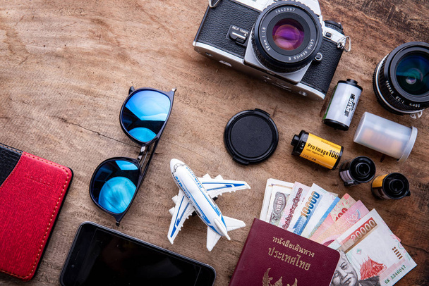 Travel concept on wooden table with film camera.Top view of beach summer accessories with copy space, Thailand passport, clothes. - Zdjęcie, obraz