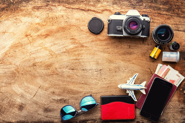 フィルムカメラ付き木製テーブルの旅行コンセプト。コピースペース、タイのパスポート、服とビーチ夏のアクセサリーのトップビュー. - 写真・画像