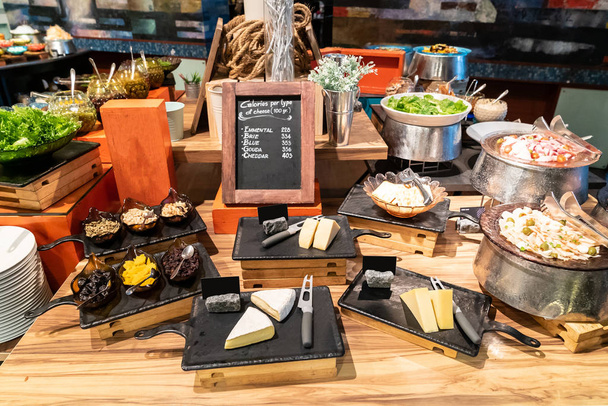 Variety of cheese on rustic wooden table in buffet line - Фото, изображение