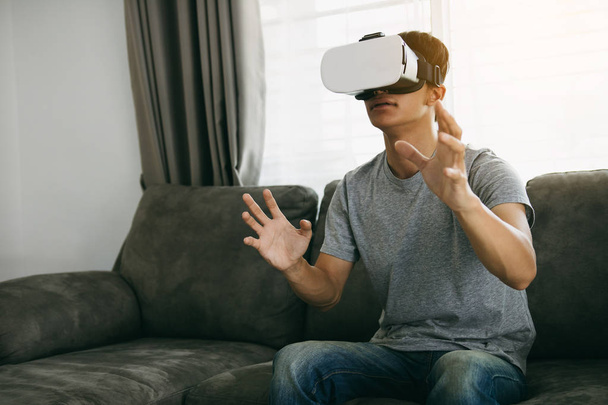 Young asian man wearing virtual reality glasses at living room f - Фото, зображення