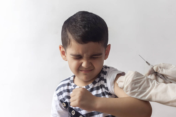 Fiatal pácienst vakcináló orvos. Kisfiú megijedt a befecskendezés. Gyermek immunizálás, gyermek védőoltás, egészségügyi koncepció. - Fotó, kép