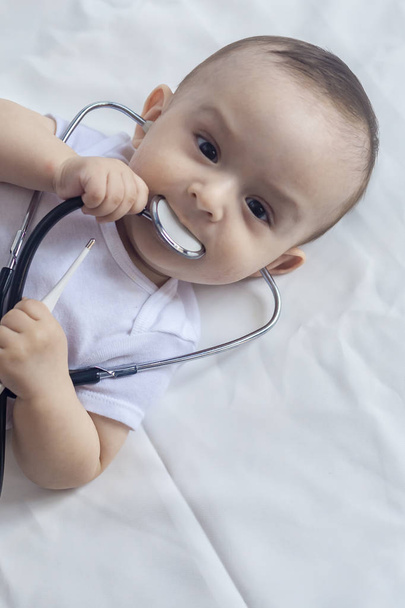 Kis aranyos baba orvos. 6 hónapos Baby Boy játszó sztetoszkóppal. Kid szórakozik, mint egy orvos - Fotó, kép