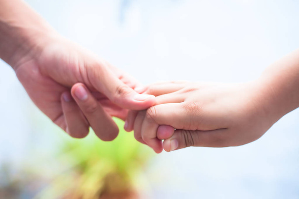 Female childs hand holding the hand of elder male shot with bokeh background and horizontal. Concept of fathers day 16th June. - Photo, image