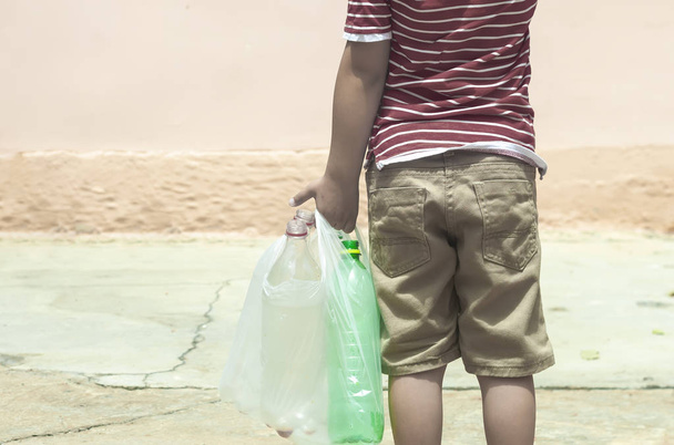 Plastic vervuiling op het land. Kleine jongen verzamelen van plastic flessen. Kid Carry garbage Bag. Vrije ruimte - Foto, afbeelding