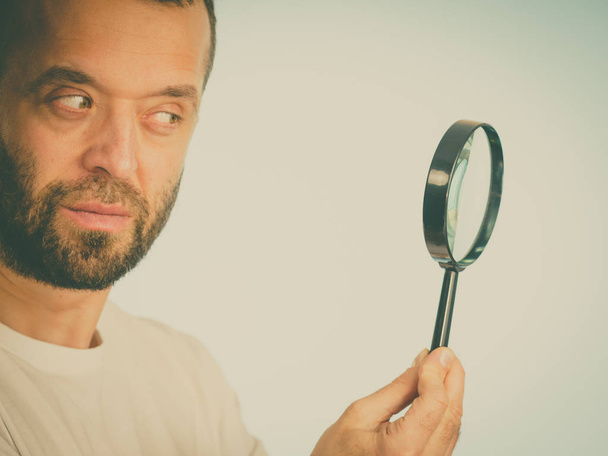 Curious man using magnifying glass - Foto, afbeelding