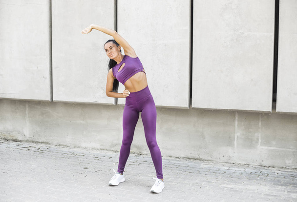 Fitness woman stylish clothes exercise in the city street over gray background. Sports in fashion girl on a rest after a workout. Urban style. Healthy lifestyle. - Foto, Bild