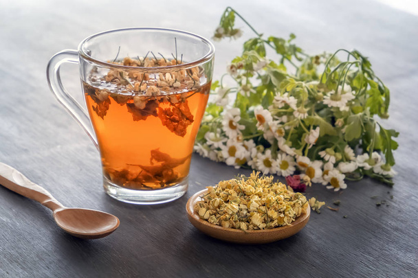 Herbal tea with pharmaceutical chamomile on a gray wooden table. Close-up - Photo, Image