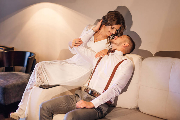 la pareja en ropa de fiesta se sientan en el sofá y quieren besar
 - Foto, Imagen