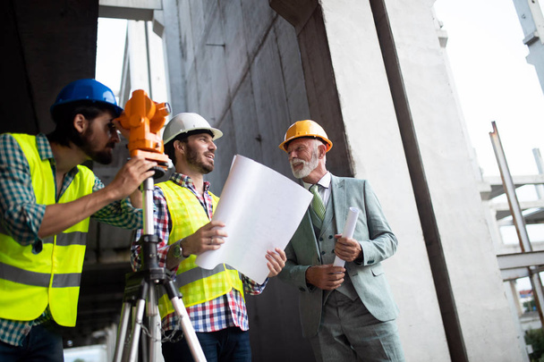Confident team of architects and engineers working together on modern construction site - 写真・画像