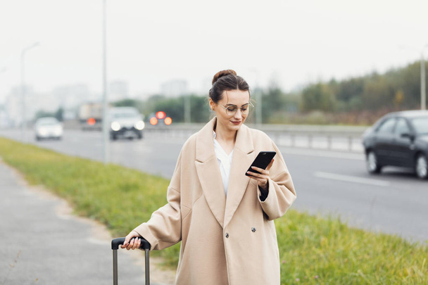 Attractive businesswoman calling a taxi at the airport - Foto, imagen