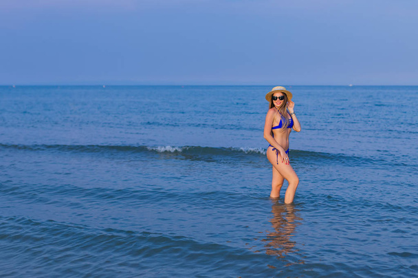  Молодая девушка в синем купальнике и солнцезащитных очках позирует в мореходе
 - Фото, изображение