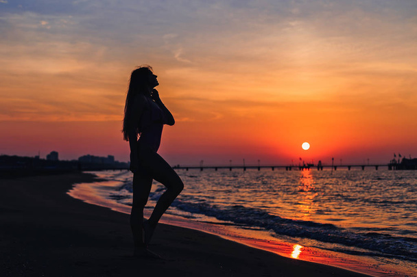 σιλουέτα ενός κοριτσιού με ένα λεπτό σχήμα στο φόντο της θάλασσας - Φωτογραφία, εικόνα