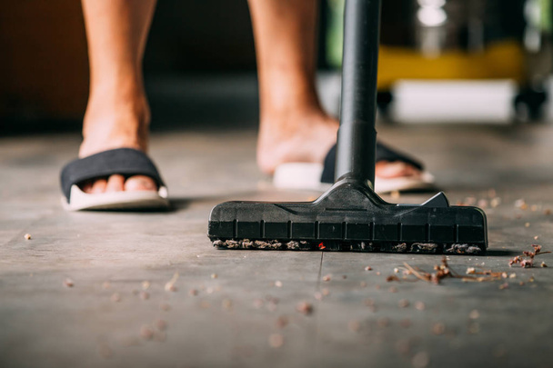 Human legs wearing sandals using vacuum cleaner inside the house - Foto, immagini