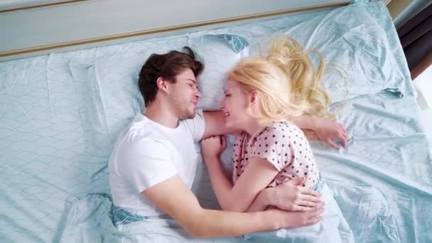 top down zoom in young smiling couple in bed in the morning - Filmati, video