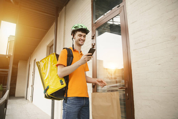 Giovane uomo come un corriere consegna pizza utilizzando gadget
 - Foto, immagini