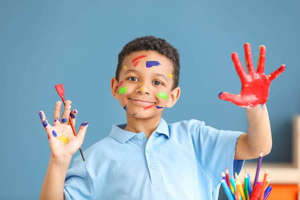 süßer afrikanisch-amerikanischer Junge mit Händen und Gesicht in Farbe zu Hause - Foto, Bild