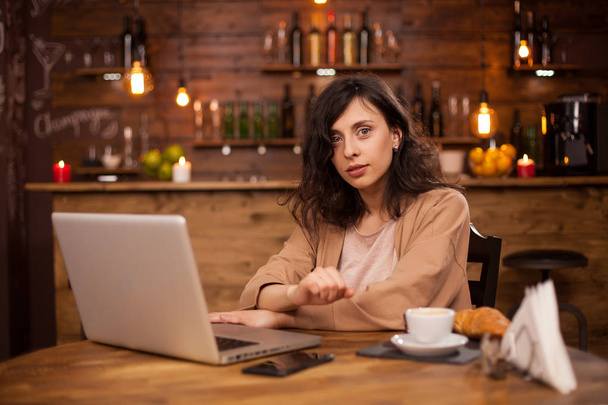 Приваблива біла жінка використовує свій ноутбук у кав'ярні з переривчастим з'єднанням
 - Фото, зображення