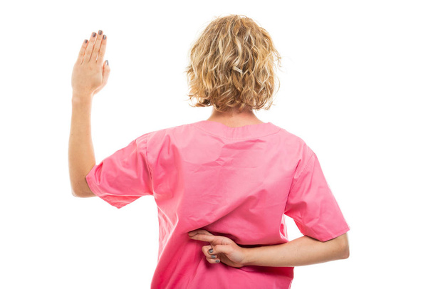 Achteraanzicht van verpleegster dragen roze scrub maken nep Oath - Foto, afbeelding