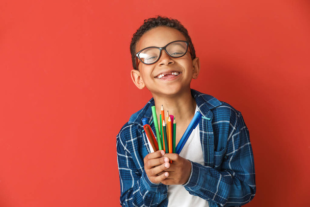 Lindo chico afroamericano con lápices y marcadores en el fondo de color
 - Foto, imagen