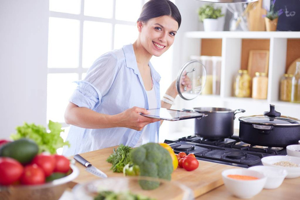 Mujer joven parada junto a la estufa en la cocina - Foto, imagen