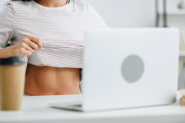 περικομμένη θέα της γυναίκας που δείχνει το σώμα της και τη χρήση του φορητού υπολογιστή  - Φωτογραφία, εικόνα