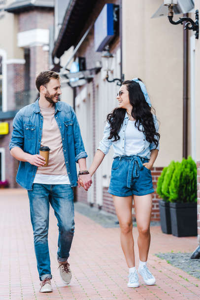 happy woman with hand in pocket walking and holding hands with man  - Foto, imagen