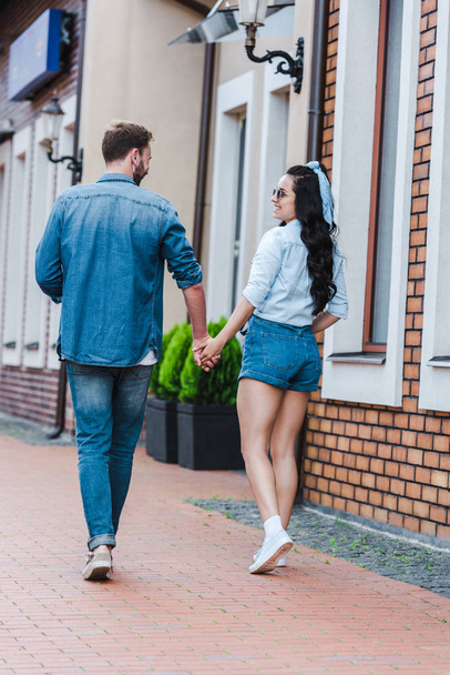 cheerful woman walking and holding hands with man  - Photo, Image