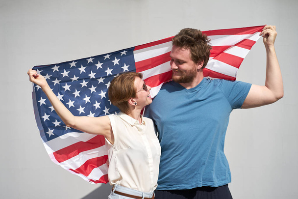 Mladí usmívající se běloši pár Američanů drží vlajku USA beh - Fotografie, Obrázek