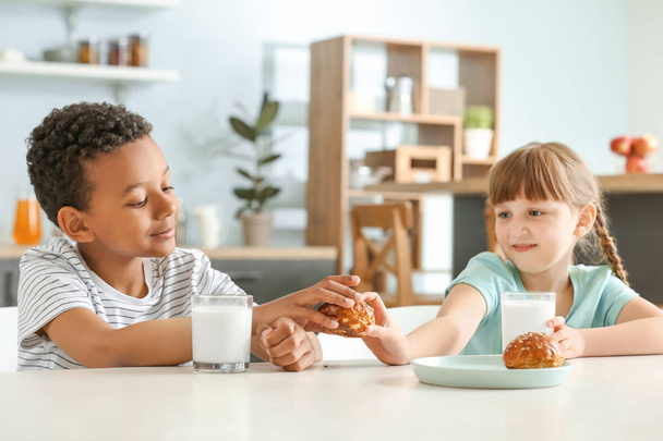 Carini i bambini piccoli con latte e panini a tavola
 - Foto, immagini