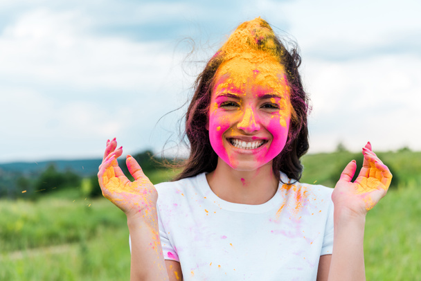 boldog nő rózsaszín és sárga Holi festéket az arcon  - Fotó, kép
