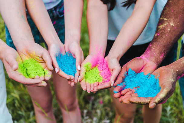 cropped view of multicultural friends holding colorful holi paints in hands  - Фото, зображення