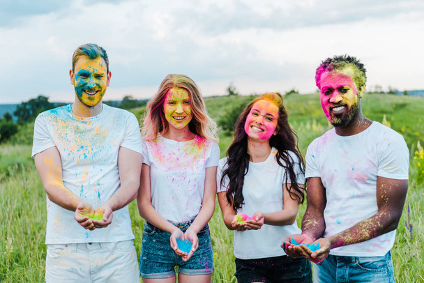 amigos multiculturais felizes segurando tintas holi coloridas em mãos
  - Foto, Imagem
