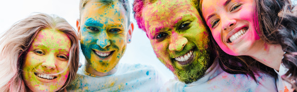 panoramiczny strzał szczęśliwych wielokulturowych przyjaciół z kolorowych farb Holi na twarzach - Zdjęcie, obraz