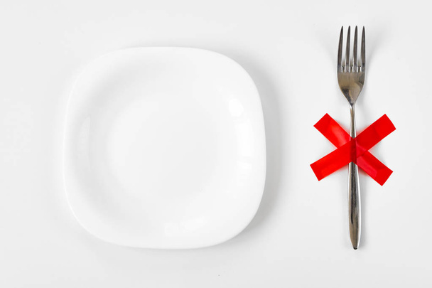 Chips in a plate and fork with red x cross on a white background. Unhealthy eating concept. - Фото, изображение