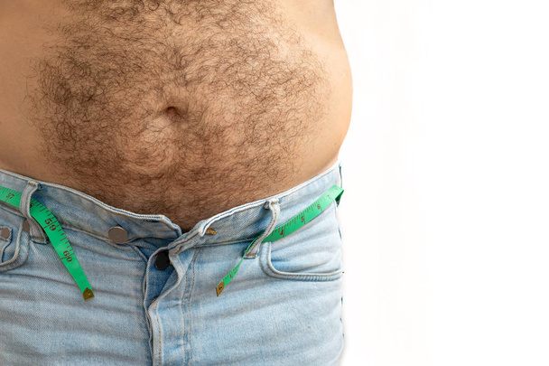 A man measures his fat belly with a measuring tape. on a white b - Photo, Image