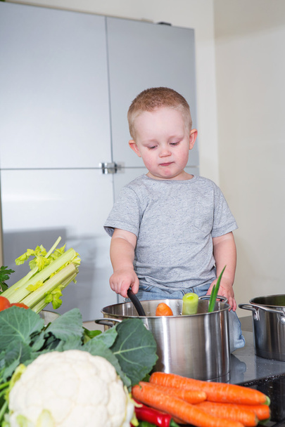 Happy child at kitchen preparing soup - Foto, Imagen