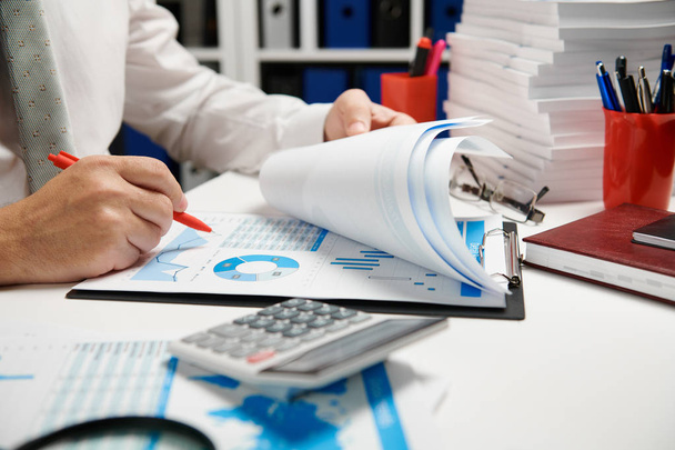 Businessman working and calculating, reads and writes reports. Office employee, table closeup. Business financial accounting concept. - Photo, Image