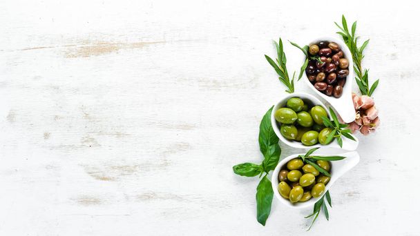 Olives in a bowl, olive oil, spices and herbs. Top view. Free space for your text. - Fotó, kép