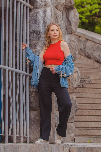 10.05.2019. Kiev, Ukraine. The young girl the blonde walks in a green garden among greens and old stairs. - Foto, Bild
