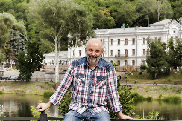 A man of mature age, bald with a beard, in a plaid shirt on the  - Valokuva, kuva