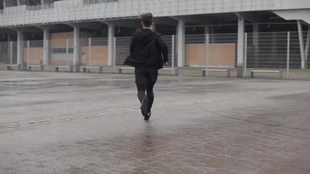 Attractive young man running outdoors slow motion. Rainy weather. Cardio exercise workout. Healthy lifestyle - running. - Video