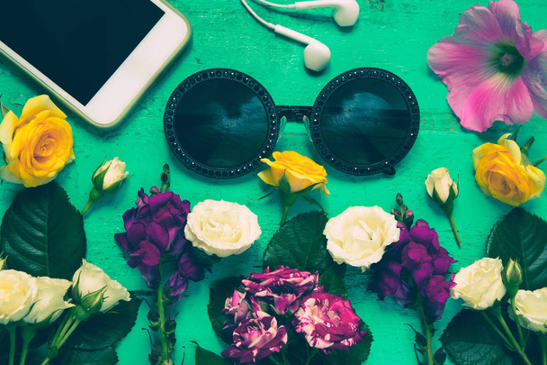 Occhiali da sole alla moda, smartphone, auricolari e fiori estivi su un
 - Foto, immagini