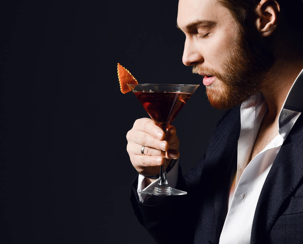 Young modern man with closed eyes going to try a delicious red cocktail drink with orange in martini glass - Foto, immagini