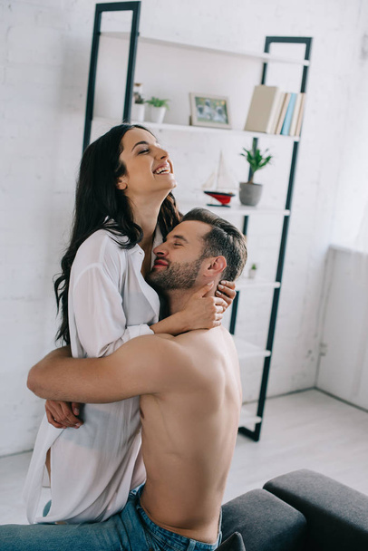 attractive and smiling woman in shirt hugging with shirtless man  - Foto, imagen